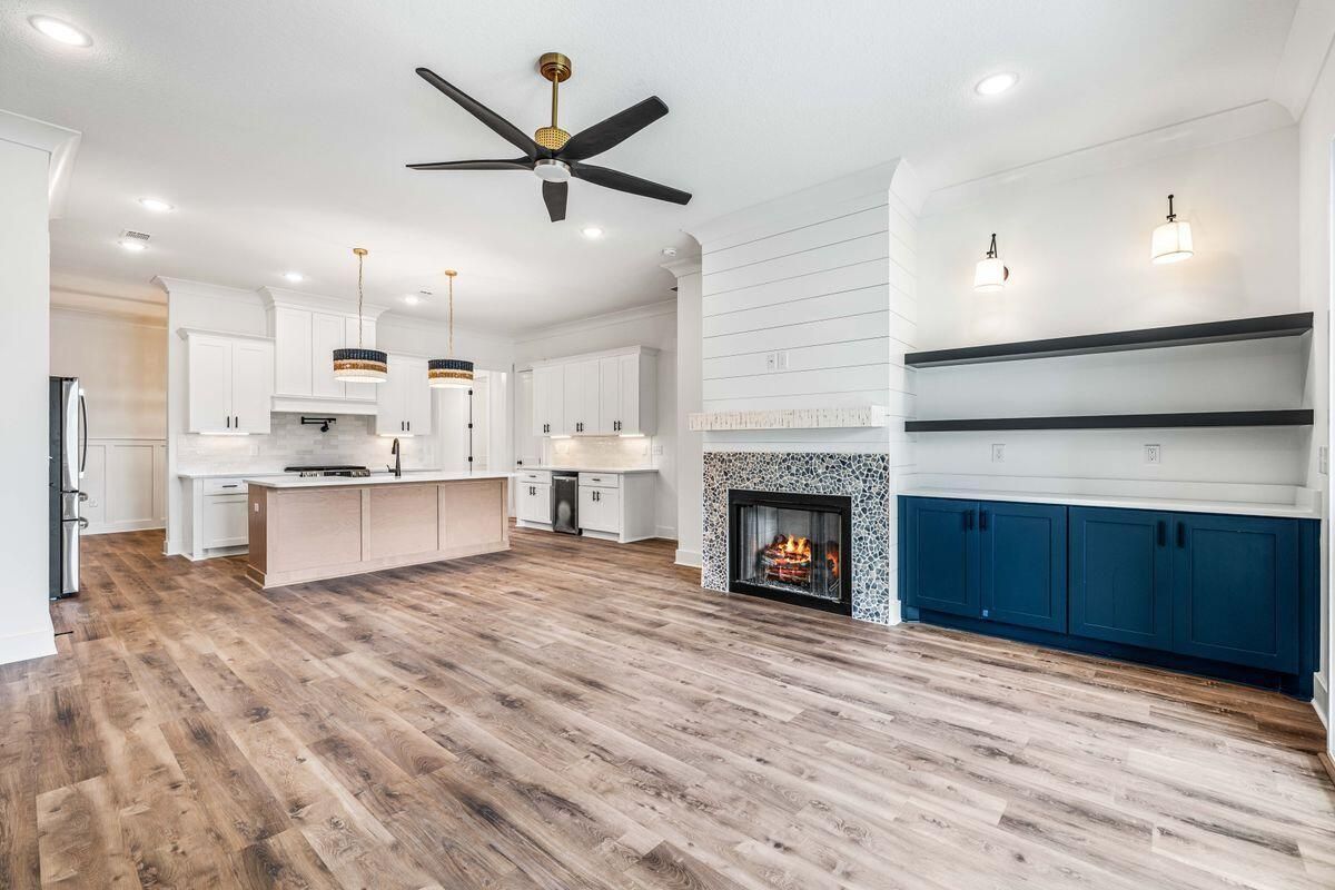 Open great room with a tiled fireplace and navy built-ins