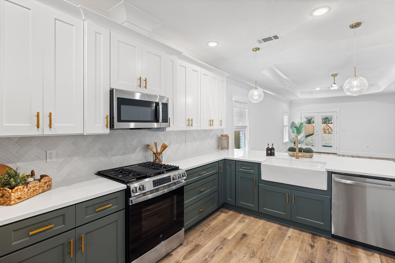 Kitchen with sage green lower cabinets, white quartz counters and gold hardware